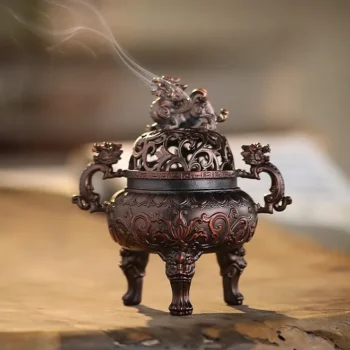 Ornate bronze incense burner with dragon motifs, smoke rising from the lid, standing on three legs.
